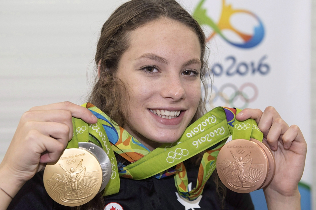 Canada's Penny Oleksiak from Toronto holds up her four medals a gold silver and two bronze she won at the 2016 Summer Olympics during a news conference Sunday