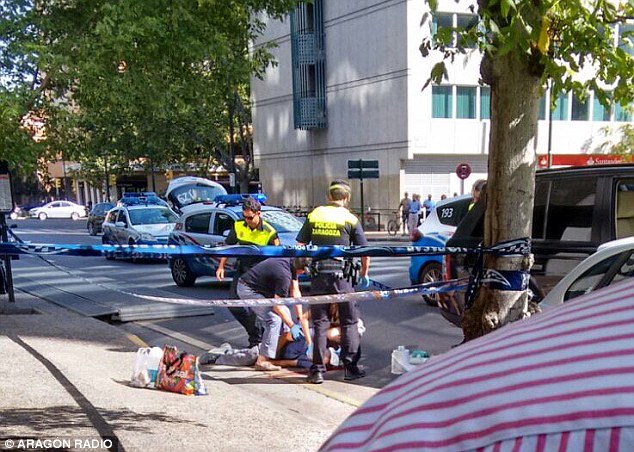 One of the victims of the shooting is seen being attended to by police after they were gunned down in the street