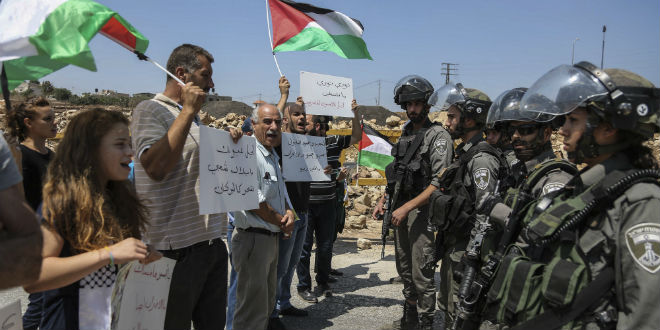 Palestinian protesters hold flags as they argue with Israeli border policemen during a protest in the West Bank village of Nabi Saleh near Ramallah