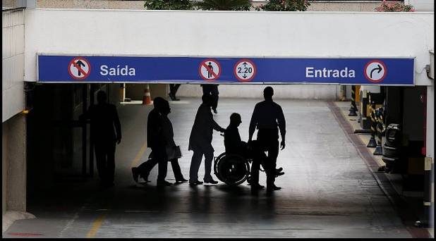 Pat Hickey in wheelchair is escorted by police to a waiting car at the Hospital Samaritano in Rio de Janeiro