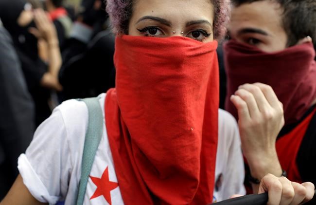 A demonstrator with her face covered marches during a protest on the route of the Olympic torch against the money spent on the Rio's 2016 Summer Olympics in Niteroi Brazil Tuesday Aug. 2 2016. The three-month torch relay across Brazil will end