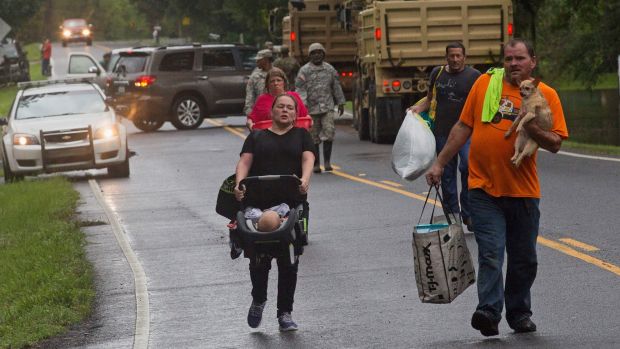 People arrive to be evacuated by members of the Louisiana Army National Guard near Walker Louisiana after heavy rains