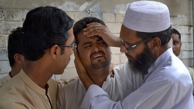 People comfort a man mourning the death of a family member who was killed in suicide bombing in Quetta