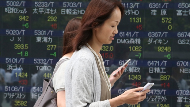 People walk by an electronic stock board of a securities firm in Tokyo Monday