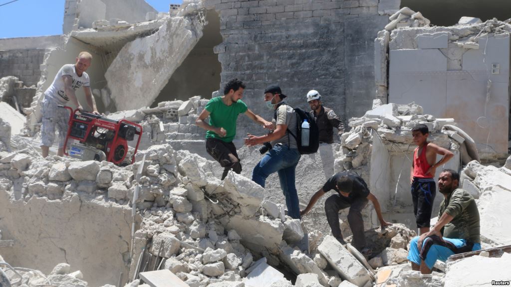 People walk on the rubble of a site hit by a barrel bomb in the rebel-held area of Old Aleppo Syria