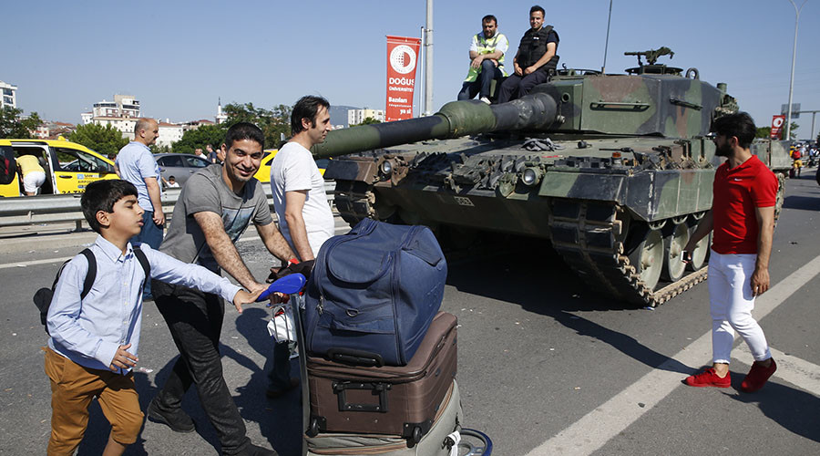 People walk past Turkish police officers sitting on a Leopard 2 tank in Istanbul Turkey