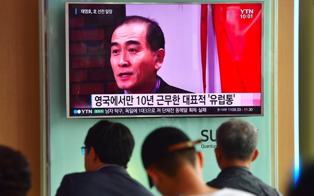 People watching a news broadcast showing file footage of Thae Yong-ho at a railway station in Seoul