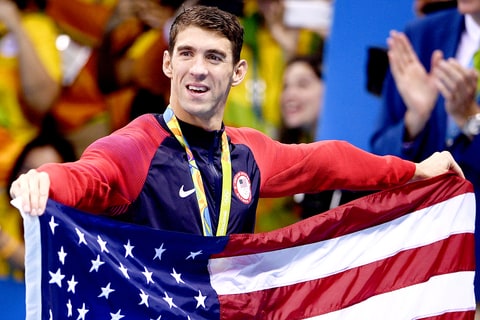 USA's gold medallist Michael Phelps holds the US flag after the podium ceremony of the Men's swimming 4 x 100m Medley Relay Final at the Rio 2016 Olympic Games at the Olympic Aquatics Stadium in Rio de Janeiro