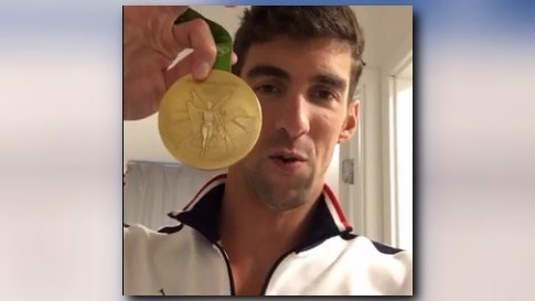 Phelps shows off one of his gold medals from earlier this week