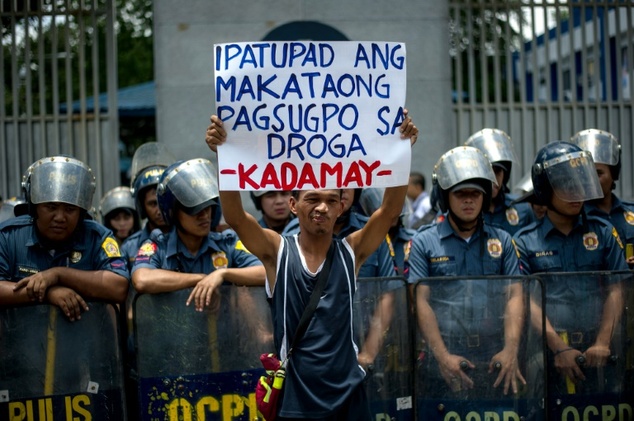 An activist hold a banner in front of the Philippine National Police headquarters during a protest condemning extra-judicial killings in President Rodrigo Du