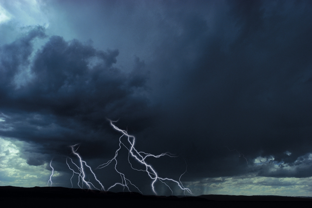 Multiple lightning bolts over rural landscape