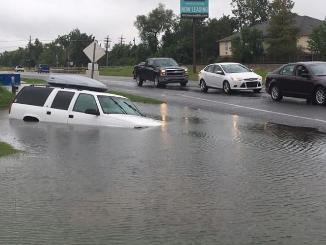 Vehicles pass a submerged car in a ditch on Highway 30 near Brightside La. on Saturday