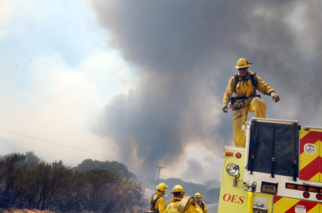 A strike team prepares to deploy along Highway 173 during a wildfire in Hesperia Calif. on Monday Aug. 8 2016. Smoke plumes roiling from flaming ridges