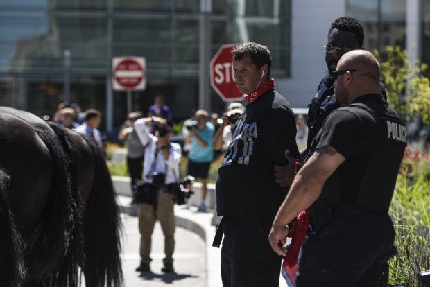 Police handcuff a Trump supporter with his own Confederate flag after opposing protesters pushed him