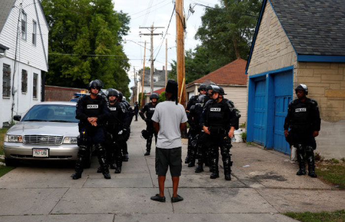 Police in riot gear assemble in an alley after disturbances following the police shooting of a man in Milwaukee Wisconsin on Monday. — AP