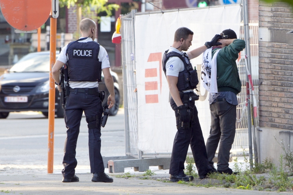 Police officers check the identification of a man near the police headquarters in Charleroi Belgium on Saturday