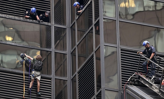 A man scales the all-glass facade of Trump Tower Wednesday Aug. 10 2016 in New York. A police spokeswoman says officers responded to Donald Trump's namesake skyscraper on Fifth Avenue in Manhattan. The 58-story building is headquarters to the Rep