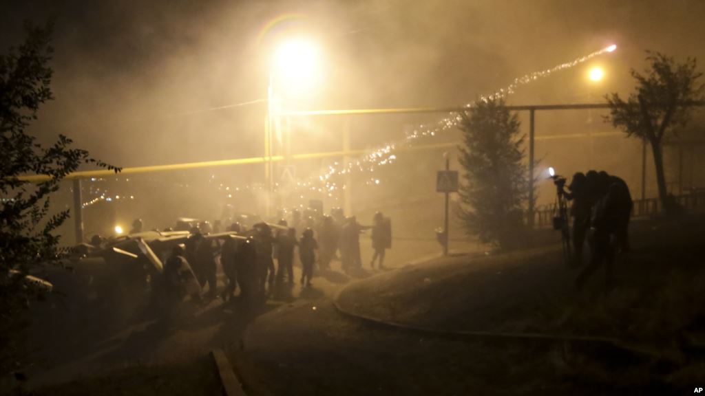 Riot police use light grenades as they confront anti-government protesters supporters of an armed group who have been holed up inside a police station in Yerevan Armenia