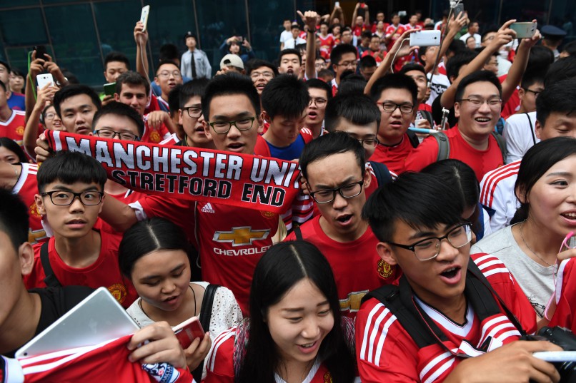 Fans of Manchester United sing songs while waiting outside the team's hotel after the match between Manchester United and Manchester City was canceled in Beijing