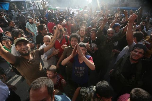 Rebel fighters and people carry the Free Syrian Army and Jabhat Fatah al Sham flags as they celebrate the news of the breaking of the siege of rebel-held areas of Aleppo Syria