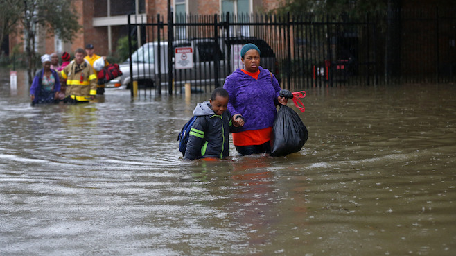 Residents wade through floodwaters from heavy rains in the Chateau Wein Apartments in Baton Rouge La. Friday Aug. 12 2016. Heavy downpours pounded parts of the central U.S. Gulf Coast on Friday forcing the rescue of dozens of people stranded in homes