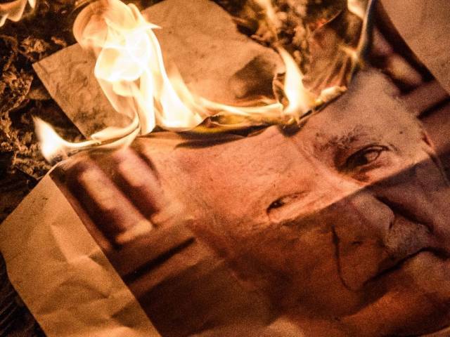 Pro-Erdogan supporters burn a poster picturing US-based preacher Fethullah Gulen during a rally at Taksim square in Istanbul