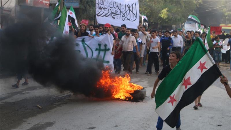 Protesters in rebel-held Aleppo carry FSA flags and burn tyres which they said are used to create smoke cover from warplanes