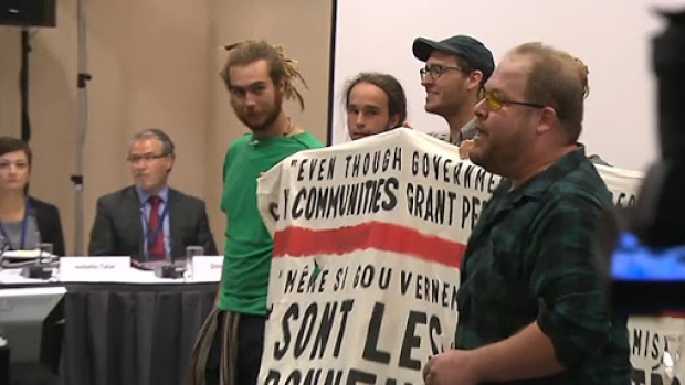 Protesters unfurled an anti Energy East banner after disrupting the National Energy Board proceedings in Montreal