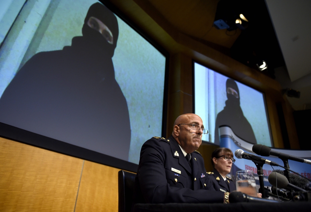 Video footage showing Aaron Driver is seen behind Royal Canadian Mounted Police Deputy Commissioner Mike Cabana left and Commander Jennifer Strachan during a press conference in Ottawa on Thursday