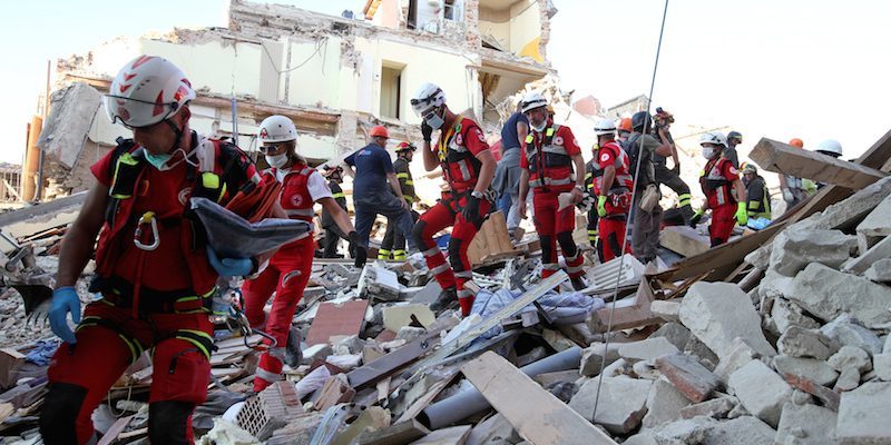 Rescuers walk through rubble following the earthquake in Amatrice