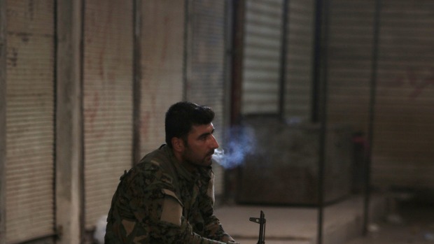 A Syria Democratic Forces fighter smokes a cigarette in the city of Manbij in Aleppo Governorate