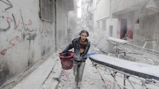 A boy carries his belongings at a site hit by what activists said was a barrel bomb dropped by forces loyal to Assad in Aleppo's al Fardous district. Reuters