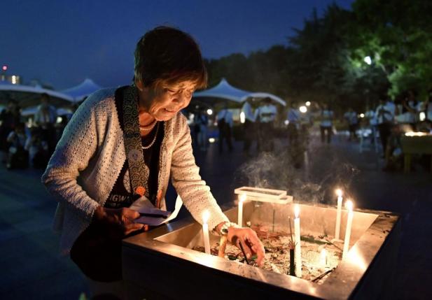 A woman lights up a candle in front of the cenotaph for the victims of the 1945 atomic bombing at Peace Memorial Park in Hiroshima western Japan in this