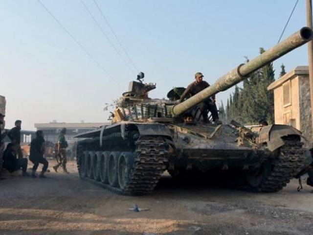 Rebel fighters ride a tank in an artillery academy of Aleppo Syria