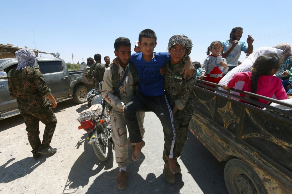 ReutersSyrian Democratic Forces fighters help a civilian as residents evacuate the southern districts of Manbij city after the SDF advanced into