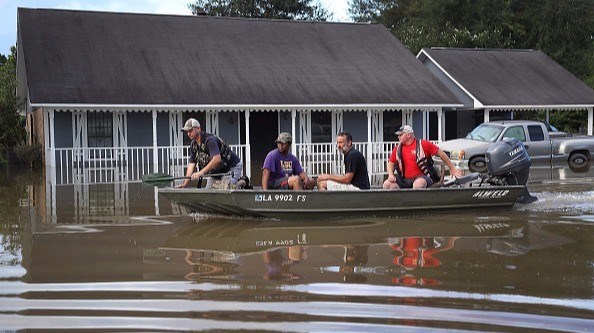 Richard Schafer navigates a boat past a flooded home