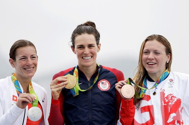 Gold medalist Gwen Jorgensen of the United States center poses with silver medalist Nicola Spirig Hug of Switzerland left and bronze medalist Vicky Holland of Great Britain after they competed in the women's triathlon event on Copacabana beach