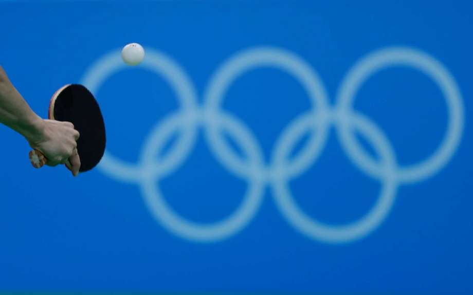 An athlete throws a backhand in front of the Olympic rings during a table tennis training session ahead the 2016 Summer Olympics in Rio de Janeiro Brazil Thursday Aug. 4 2016