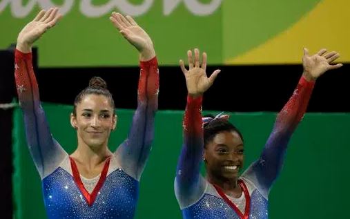 United States&#039 Simone Biles gold medal winner and silver medallist and compatriot Aly Raisman left wave after final results for floor routine during the artistic gymnastics women's apparatus final at the 2016 Summer Olympics in Rio de Janeir