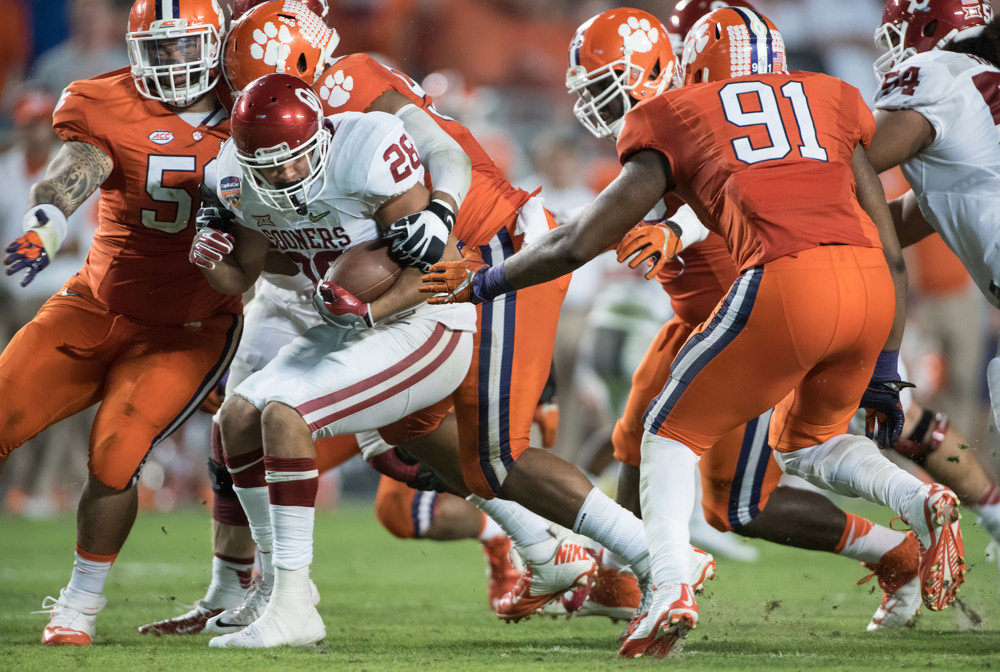 31 December 2015 Oklahoma Sooners running back Alex Ross battles with Clemson Tigers defensive tackle Scott Pagano and Clemson Tigers defensive lineman Austin Bryant in action during the College Football Playoff Semifinal- Orange Bowl Ga