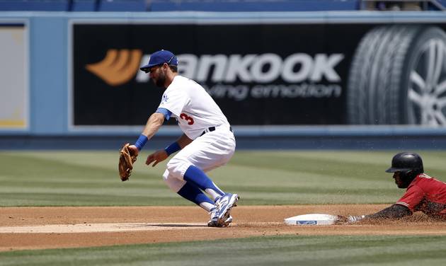 Los Angeles Dodgers second baseman Chris Taylor left misses the errant throw from catcher Yasmani Grandal as Arizona Diamondbacks&#039 Jean Segura right steals second then advances to third on the throw during the first inning of a baseball game