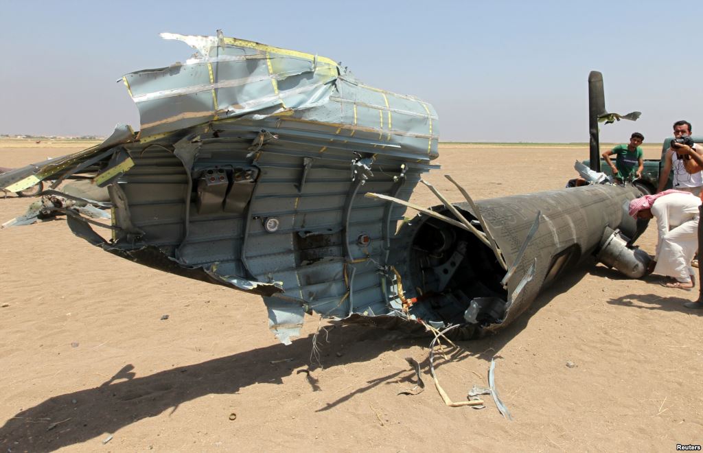 FILE- Men inspect the wreckage of a Russian helicopter that had been shot down in the north of Syria's rebel-held Idlib province Syria Aug. 1 2016