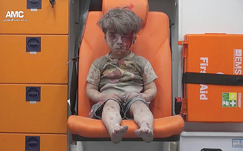 ALEPPO In this frame grab taken from video provided by the Syrian anti-government activist group Aleppo Media Center, a child sits in an ambulance after being pulled out of a building hit by an airstrike on Wednesday. —AP