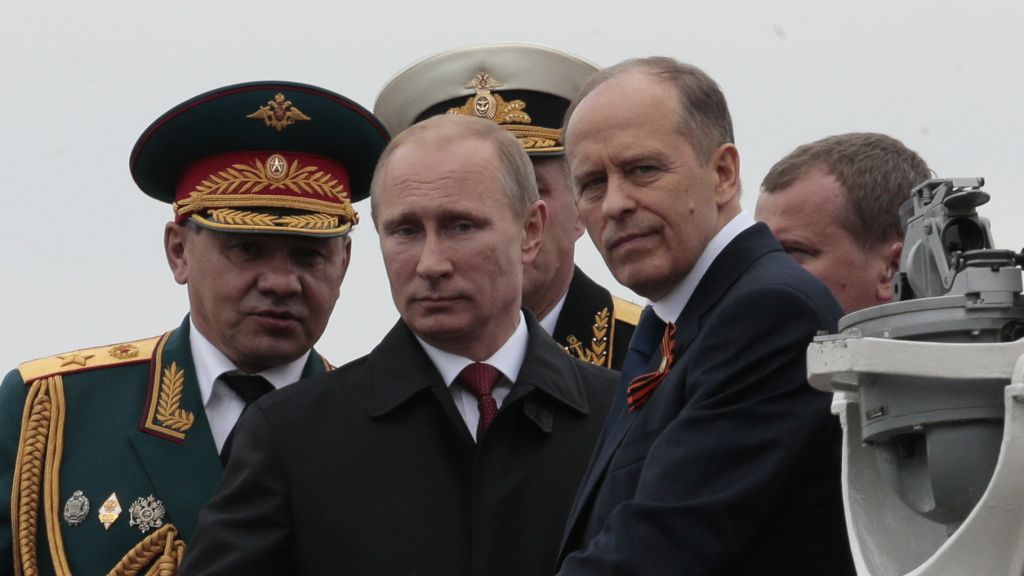 Russian President Vladimir Putin center flanked by Defense Minister Sergei Shoigu left and Federal Security Service Chief Alexander Bortnikov right arrives on a boat after inspecting battleships durin