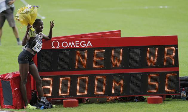 Ruth Jebet of Bahrain poses next to the board showing her result after she set a new world record in the women's 3,000-meter steeplechase event at the IAAF Diamond League athletics meeting at Stade de France stadium in Saint Denis north of Paris Fr