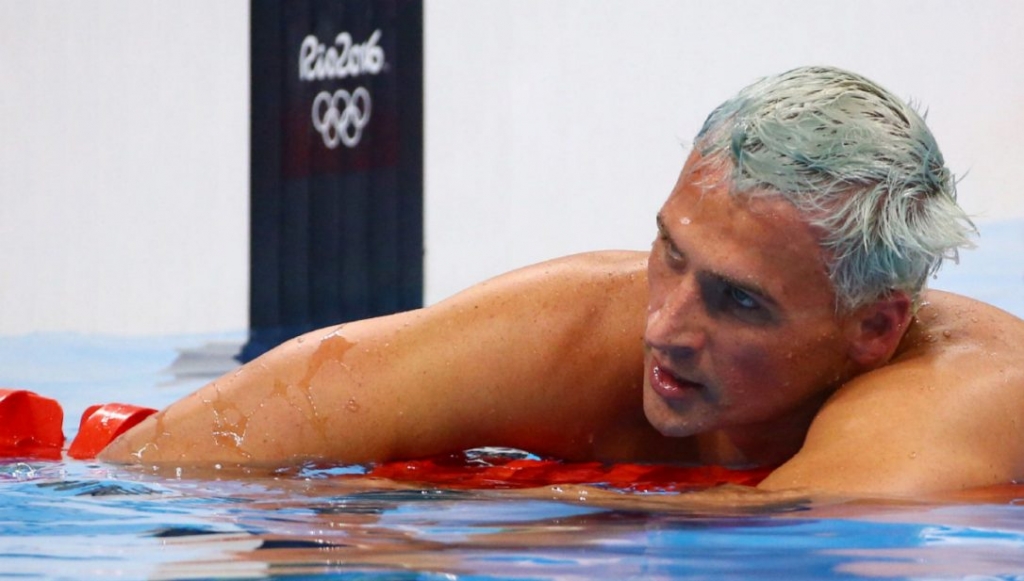 Ryan Lochte initially said that he and fellow swimmers were robbed at gunpoint in a taxi by men with a police badge as they returned to the Olympic Village from a party Aug. 15