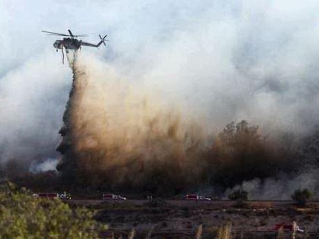 A helitanker does a water drop on hot spots during a wildfire near Cajon Boulevard in Devore California