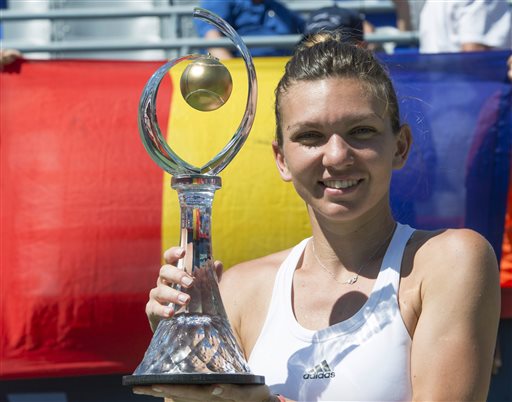 Simona Halep of Romania holds up her trophy in front of her national flag after defeating Madison Keys of the United States in the final of the Rogers Cup tennis tournament Sunday