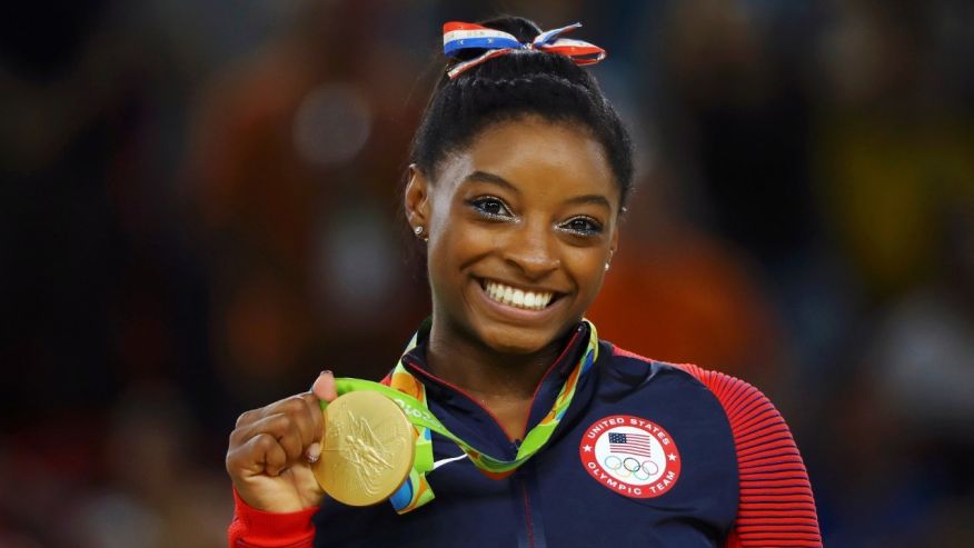 Simone Biles of USA poses with her gold medal on the podium