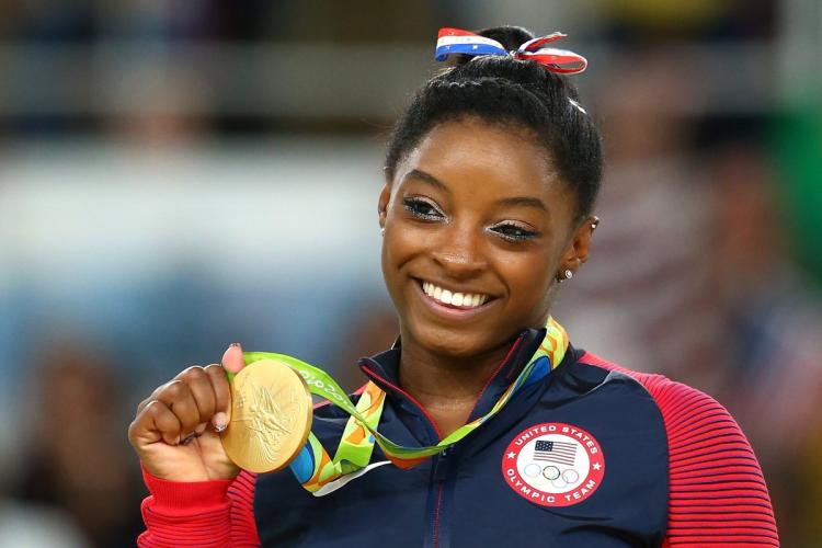 Simone Biles needed a hand from Michael Phelps once the medals started piling